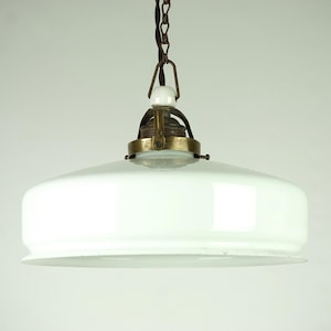 May include: A white glass pendant light fixture with a brass and metal chain and a white porcelain socket.