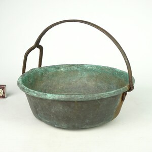 May include: A vintage copper pot with a metal handle. The pot has a green patina and is in good condition.