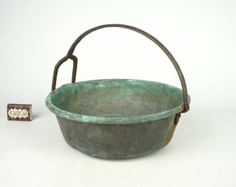 May include: A vintage copper pot with a metal handle. The pot has a green patina and is in good condition.