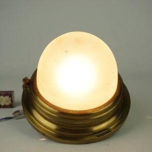 May include: A brass ceiling light fitting with a frosted glass globe. The light is on and the globe is illuminated.