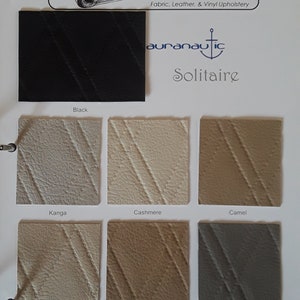 May include: A fabric sample card featuring various upholstery swatches. The card includes a black swatch and samples in shades like Kanga, Cashmere, Camel, Sesame, Tannin, and Brindle. The brand name "auranautic Solitaire" is visible.