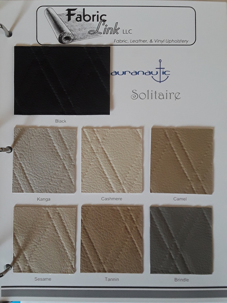 May include: A fabric sample card featuring various upholstery swatches. The card includes a black swatch and samples in shades like Kanga, Cashmere, Camel, Sesame, Tannin, and Brindle. The brand name "auranautic Solitaire" is visible.