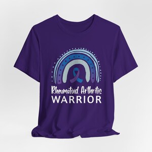 Purple graphic t-shirt with blue and purple rainbow and ribbon that says Rheumatoid Arthritis Warrior