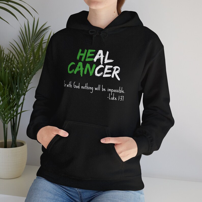 Black hoodie that says He Can Heal Cancer - For With God Nothing Will Be Impossible - Luke 1:37. The design is in green and white.