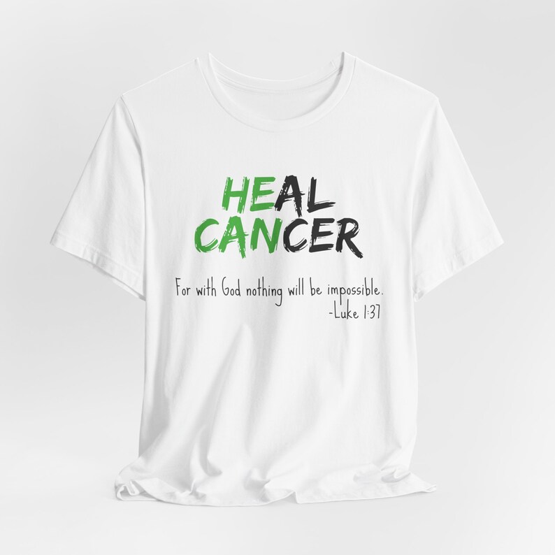 White graphic t-shirt that says He Can Heal Cancer - For With God Nothing Will Be Impossible - Luke 1:37. The design is in green and white.