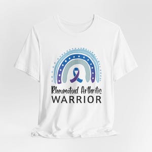 White graphic t-shirt with blue and purple rainbow and ribbon that says Rheumatoid Arthritis Warrior
