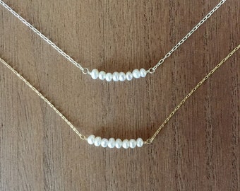 May include: Two delicate necklaces with a row of small white pearls on a silver and gold chain.