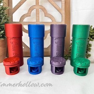 May include: Four colorful glass storage containers with matching lids. The containers are red, blue, purple, and green. Each container has the words "Glass B" and a floral design. The website address @shimmerhollow.com is at the bottom.