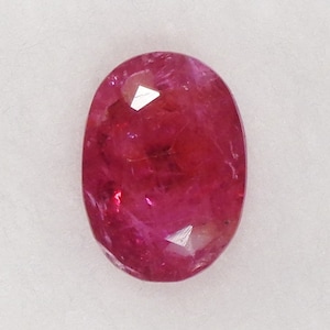 May include: A vibrant pink oval-shaped gemstone with a smooth, polished surface.