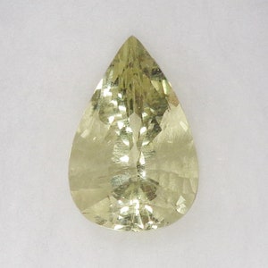 May include: A pear-shaped, light yellow gemstone with a faceted cut.
