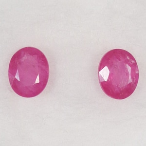 May include: Two pink oval-shaped gemstones with a faceted cut.