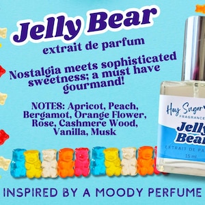 May include: A blue and white bottle of "Jelly Bear" perfume with a gummy bear theme. The bottle is labeled "Hey Sugar Fragrance Co." and "Extrait de Parfum 15 ml". The text "Nostalgia meets sophisticated sweetness; a must have gourmand!" is written in white text on a blue background. The text "NOTES: Apricot, Peach, Bergamot, Orange Flower, Rose, Cashmere Wood, Vanilla, Musk" is written in black text on a white background. The text "INSPIRED BY A MOODY PERFUME" is written in white text on a blue background.