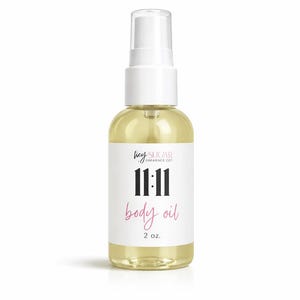 May include: A clear glass bottle of body oil with a white pump top. The label reads "hey sugar ambiance co." above the numbers "11:11" in black, and "body oil" in pink. The bottle contains 2 fl oz of oil.