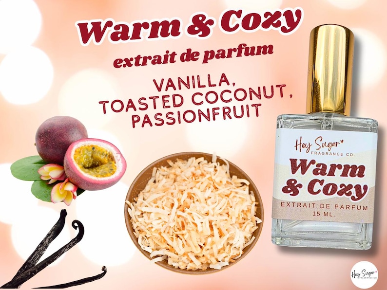 May include: A perfume bottle with a gold cap and a label that reads "Warm & Cozy" with "extrait de parfum" and "15 ML." The image includes vanilla beans, passion fruit, and toasted coconut, with the scent notes listed.