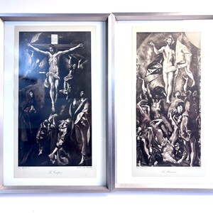 May include: Two framed black and white art prints by El Greco. The left print, titled Le Crucifix, depicts a crucifixion scene. The right print, titled La Résurrection, shows a resurrection scene. Both prints are housed in silver metal frames.