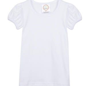 May include: White short-sleeved t-shirt with a round neckline and puffed sleeves. The shirt has a small tag with the text "Baby Bows" and "100% combed cotton made in China".