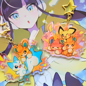 May include: Two colourful keychains featuring Pokemon characters. The first keychain has a yellow Pikachu, a pink Eevee, and a brown Flareon. The second keychain has a blue and white Vaporeon, a white and pink Espeon, and a white and blue Glaceon. Both keychains have a gold star charm.