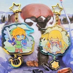Peut inclure: Deux porte-clés colorés représentant des personnages de dessin animé de la série de jeux vidéo The Legend of Zelda. Le porte-clés de gauche représente Link, un jeune garçon aux cheveux blonds, vêtu de vert et tenant une épée. Le porte-clés de droite représente Zelda, une jeune fille aux cheveux blonds, vêtue d'une robe blanche et tenant ses mains jointes en prière. Les deux porte-clés ont un charme d'étoile dorée en haut.