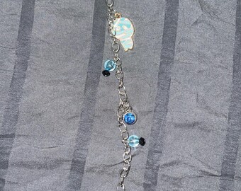 Op de afbeelding: Een zilveren ketting met blauwe en zwarte kralen en een zwarte spookbedel.