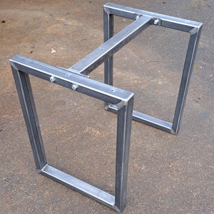 May include: A metal table base with a square top and four legs. The base is made of welded steel and has a grey finish.