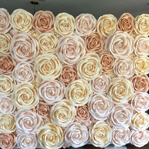 May include: A wall covered in large, paper roses in shades of cream and peach. The roses are arranged in a staggered pattern, creating a beautiful and elegant backdrop.