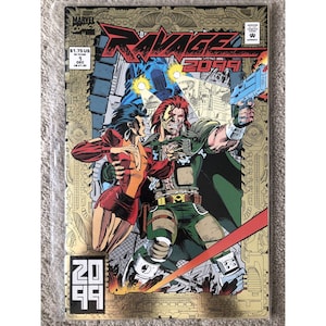 May include: A comic book cover featuring a futuristic scene with three characters. The cover is gold and black with the title "RAVAGE 2099" in red and white. The characters are a woman in a red and black outfit, a man in a green and black outfit, and a robot.