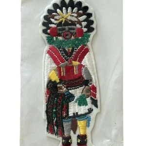 May include: Embroidered iron-on patch featuring a colorful Native American figure in traditional clothing with a headdress. The figure is holding a rattle and a feather.
