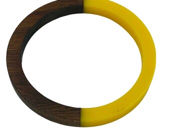 May include: A wooden and yellow bangle bracelet. The bracelet is half dark brown wood and half bright yellow.