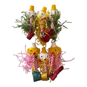 May include: Six party blowers featuring plastic clown heads with yellow or white hats, attached to patterned paper tubes and rolled-up mouthpieces. The blowers are surrounded by shredded paper in green, yellow, and pink colors, creating a festive display.