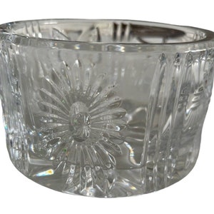 Op de afbeelding: Een glazen kom met een geslepen glasontwerp met een madeliefjespatroon. De kom heeft een ronde vorm en een gladde rand.