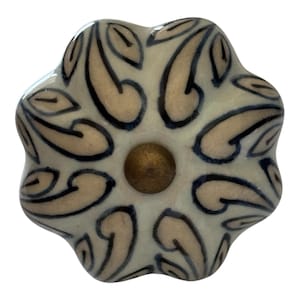 May include: A flower-shaped ceramic cabinet knob with a glossy cream-colored finish. The surface features a repeating dark blue hand-painted leaf pattern radiating from a central circular brass-toned metal hardware piece at the very middle.