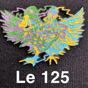 May include: A colorful enamel pin featuring two stylized ducks with intricate details in shades of green, blue, yellow, and purple. The pin is set against a black background.