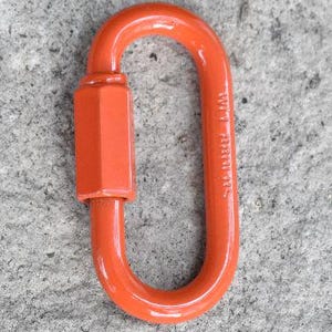 May include: An orange oval-shaped quick link connector featuring a threaded hexagonal nut closure on one side. The metal hardware has a smooth, glossy finish and includes embossed text on the side of the frame, showing a durable construction.