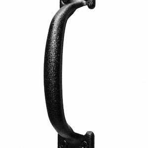 May include: A black metal door handle with a textured finish and a curved grip. The handle features two rectangular mounting plates at the top and bottom, each secured with two visible black screws, providing a sturdy and functional design.