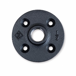 May include: A circular black metal floor flange with a textured finish. The component features four countersunk screw holes, a central threaded opening, a diamond-shaped logo with the letter S, and the fraction 1/2 embossed on the surface.