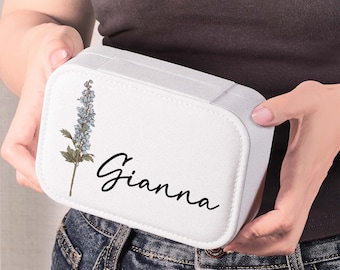 May include: A white rectangular travel jewelry case with a textured finish. The front features a printed illustration of a blue delphinium flower and the name Gianna written in a black cursive script font. The case has rounded corners.
