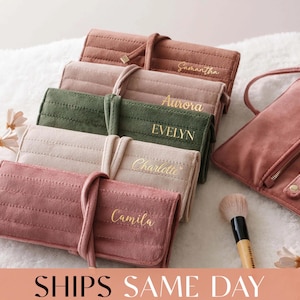 May include: A collection of five rectangular, quilted velvet jewelry rolls in shades of dusty rose, beige, and olive green. Each roll features a wrap-around tie closure and is personalized with gold script names: Samantha, Aurora, Evelyn, Charlotte, and Camila.