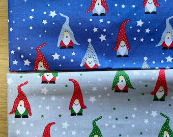 May include: Two pieces of fabric with a repeating pattern of gnomes and stars. One fabric is blue with white stars and gnomes wearing red and gray hats. The other fabric is gray with white stars and gnomes wearing red and green hats.