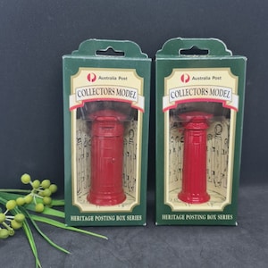May include: Two red miniature Australian post boxes, labeled "Collectors Model" and "Heritage Posting Box Series", are displayed in their original packaging. The boxes are green with a clear plastic front, showcasing the red post boxes.