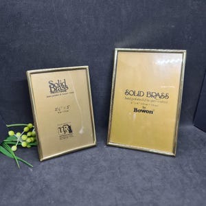 May include: Two rectangular solid brass photo frames. One frame is 3.5" x 5" and the other is 4" x 6". Both frames have a gold finish and the text "Solid Brass" is visible on the front.