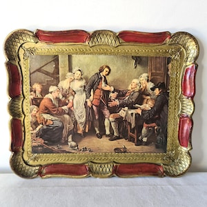 May include: A decorative tray featuring a framed print of a historical scene. The tray has a red and gold ornate border. The print shows a group of people in a room, with a man in a red coat at the centre. The tray is likely vintage.