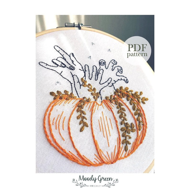 May include: Embroidered design of two hands reaching out of a pumpkin with green vines. The design is in a white embroidery hoop. The text "PDF pattern" is in the upper right corner of the image.