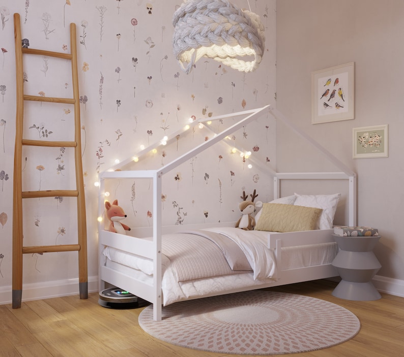 May include: White wooden bed frame with a house-shaped canopy, featuring a white and gray striped comforter, a yellow pillow, and a stuffed fox toy. The bed is decorated with string lights and a white knitted pendant light.