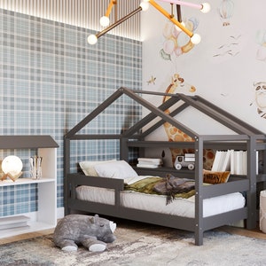 May include: A gray wooden house-shaped bed frame with a white mattress and a gray and white bookshelf next to it. The bed has a built-in shelf and a small toy truck on it. The wall behind the bed has a light blue and white plaid pattern and a white wall with a watercolor illustration of a giraffe, a raccoon, and balloons.