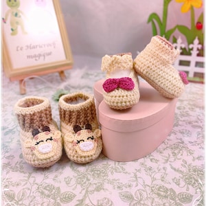 Può includere: Due paia di scarpine per neonati all'uncinetto. Un paio è beige con un fiocco rosa e l'altro paio è marrone e beige con un viso di giraffa.