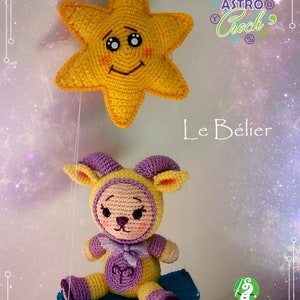 May include: A crocheted plush toy of a ram, wearing a purple and yellow outfit, sitting on a blue swing. The toy is holding a purple bow and has a yellow star above it. The text "Le B&eacute;lier" is written below the toy. The text "AstroCroch' Le Haricroch' Magique" is written in the bottom right corner.