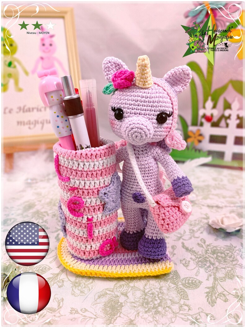 Peut inclure: Un porte-crayons en crochet en forme de licorne avec un design ray&eacute; rose et violet. La licorne a une fleur rose sur la t&ecirc;te et un sac rose. Le porte-crayons est pos&eacute; sur une base jaune.
