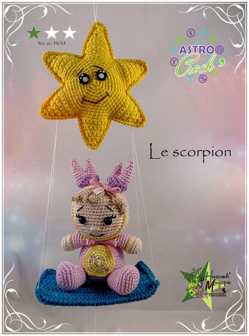 May include: A crocheted amigurumi doll representing the zodiac sign Scorpio, wearing a pink and purple outfit and sitting on a blue swing. The doll is suspended from a yellow star with a smiling face.