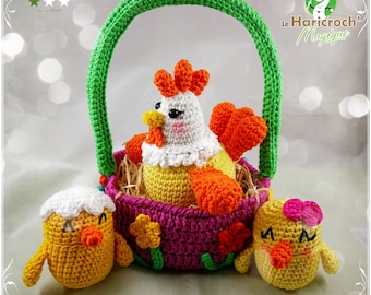 May include: A crocheted Easter basket with a green handle, filled with a yellow and orange crocheted chicken and two smaller yellow chicks. The basket is decorated with pink, green, and yellow flowers.