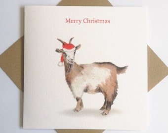 May include: A Christmas card featuring a watercolour illustration of a brown and white goat wearing a red Santa hat. The card has the text "Merry Christmas" printed in red.